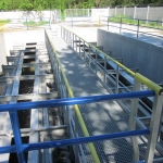 Utility walkway with composite gratings, railings and supporting structure with screens
